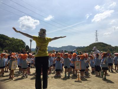 集まった園児の前で先生が両手を横に伸ばしている写真