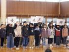 子供たちが並んで立っており、その中の四人が文字がかかれた大きな紙を頭の上に掲げている写真
