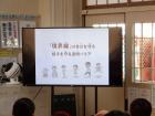 大きな液晶テレビの画面に、文字やイラストが描かれた大きな模造紙が貼られている写真