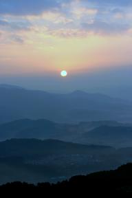 三日月山(みかづきやま)の山並みの奥から太陽の光が射している幻想的な写真