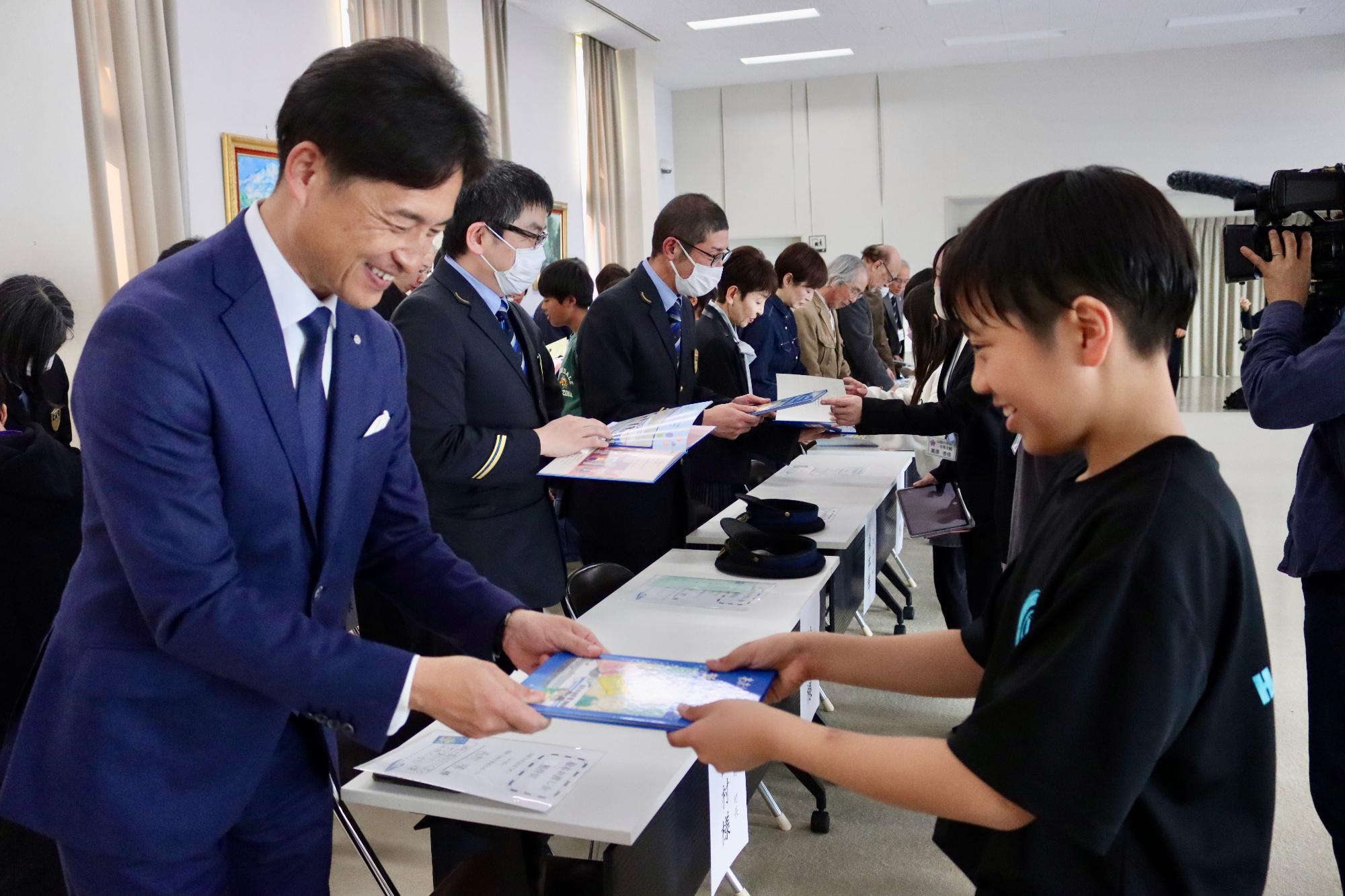 小学生が町長に絵本を手渡す様子
