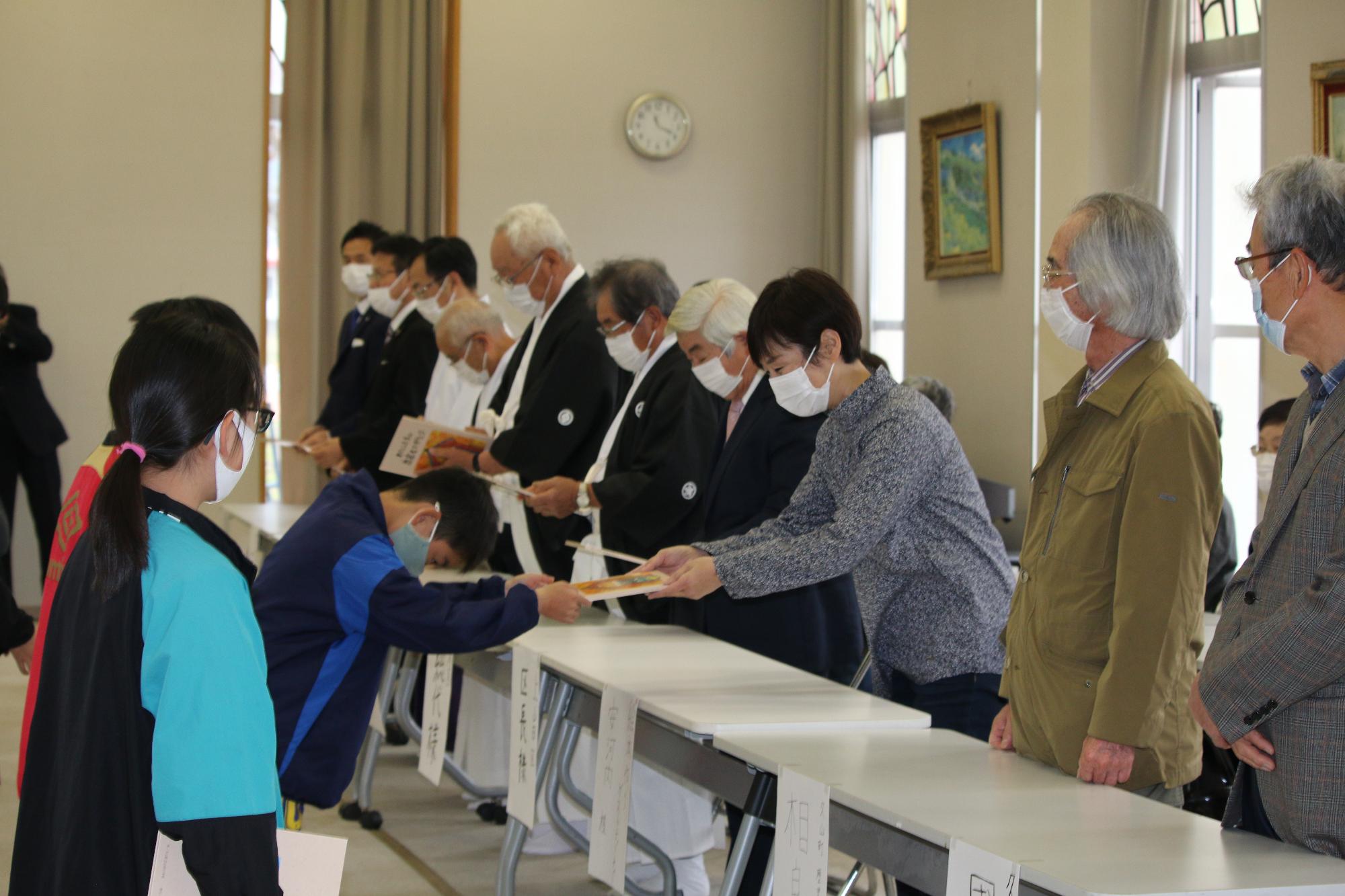 小学生が絵本を地域の皆さんなどにお渡しする様子