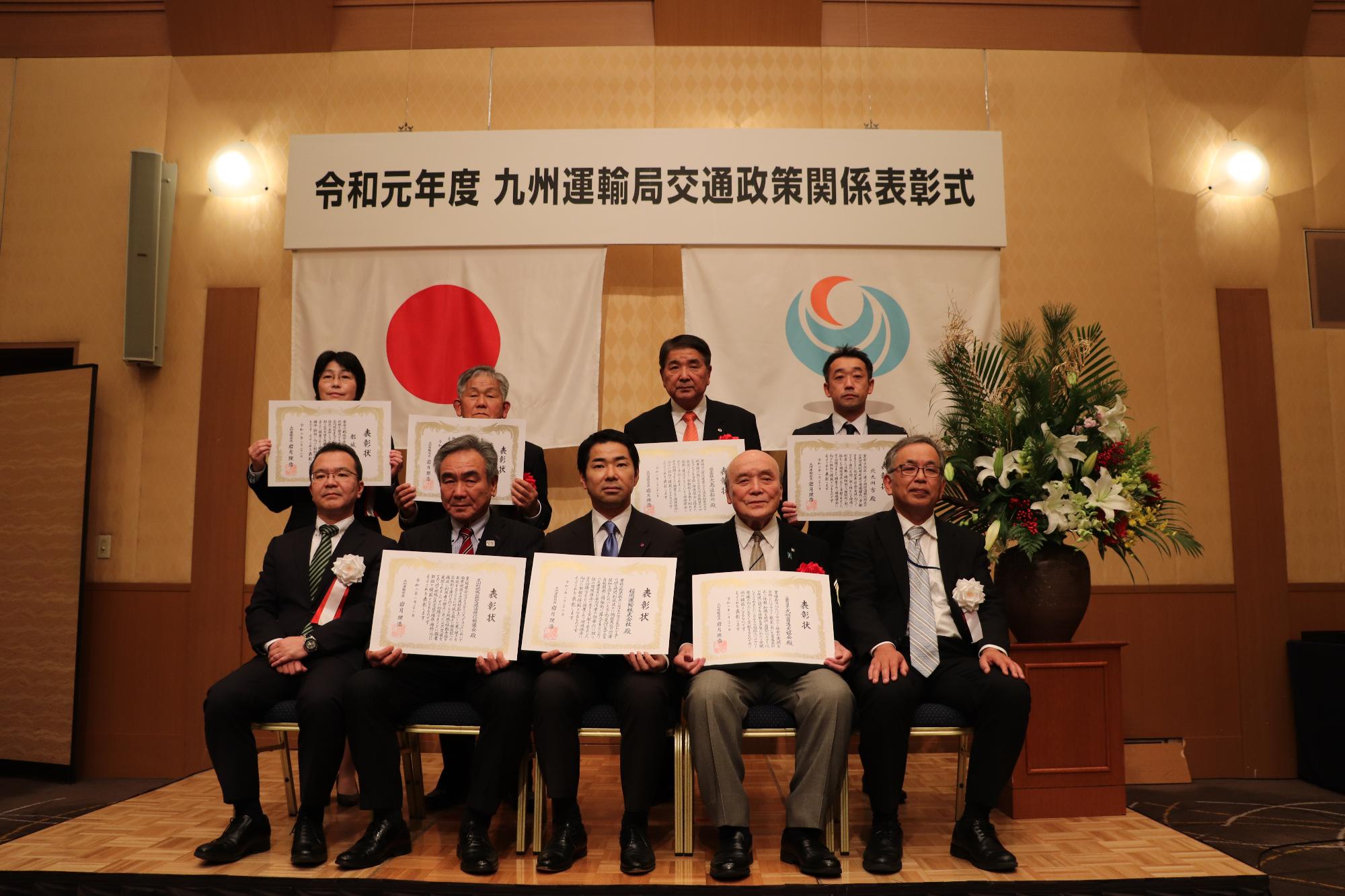 九州の中で7つの団体が受賞。表彰状を受け取った久山町副町長佐伯久雄（下段の左から2番目）