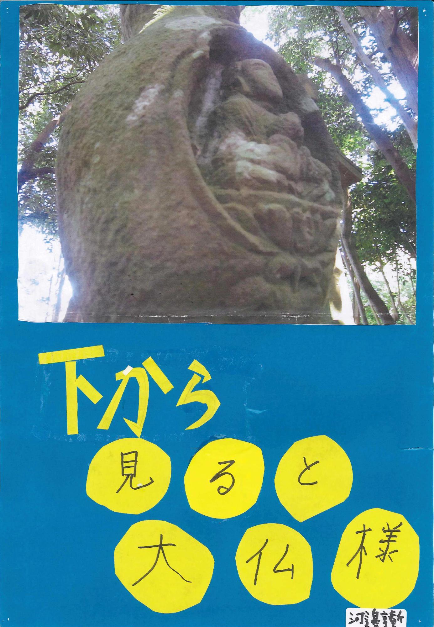 お地蔵さんを下からアップで写した写真に「下から見ると大仏様」というキャッチコピーが書かれたポスターの写真