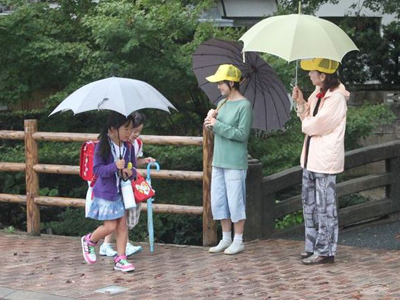 雨の日に傘を差し挨拶運動をしている様子の写真