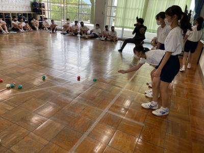 床にお手玉のようなボールを転がしてボッチャを体験している生徒たちの写真
