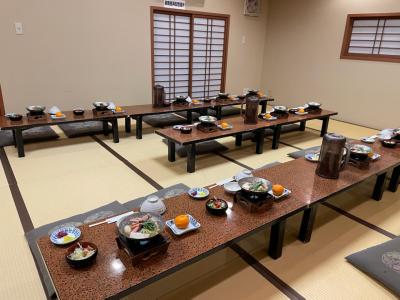 畳の広間に並べられたテーブルに配膳された夕食の写真