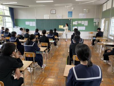 教室前方で読み聞かせをしている女性の話を真剣に聞いている中学生たちの後ろ姿の写真