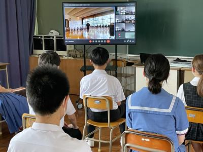 教室に並べられた椅子に生徒たちが座り、室内前方に置かれたテレビで部活動選手激励会の様子を見ている写真