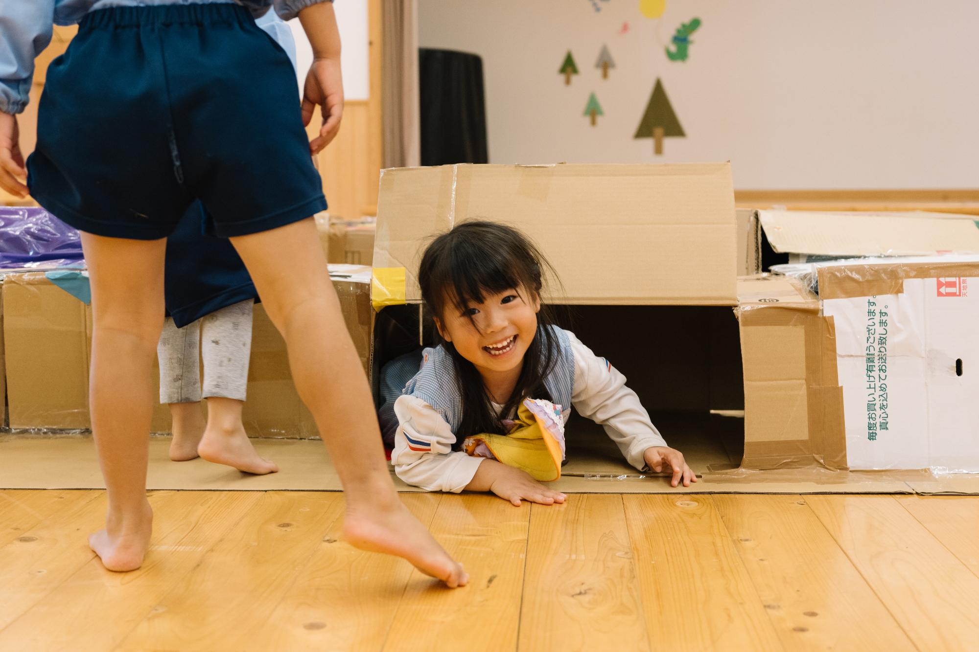 段ボールで作った迷路から出てきた子ども