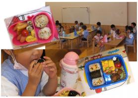 ピンクのお弁当と青のお弁当、席に座り子供達がお弁当を食べている写真
