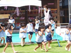 口元を両手で押さえながら園庭へ向かう子供たちの写真