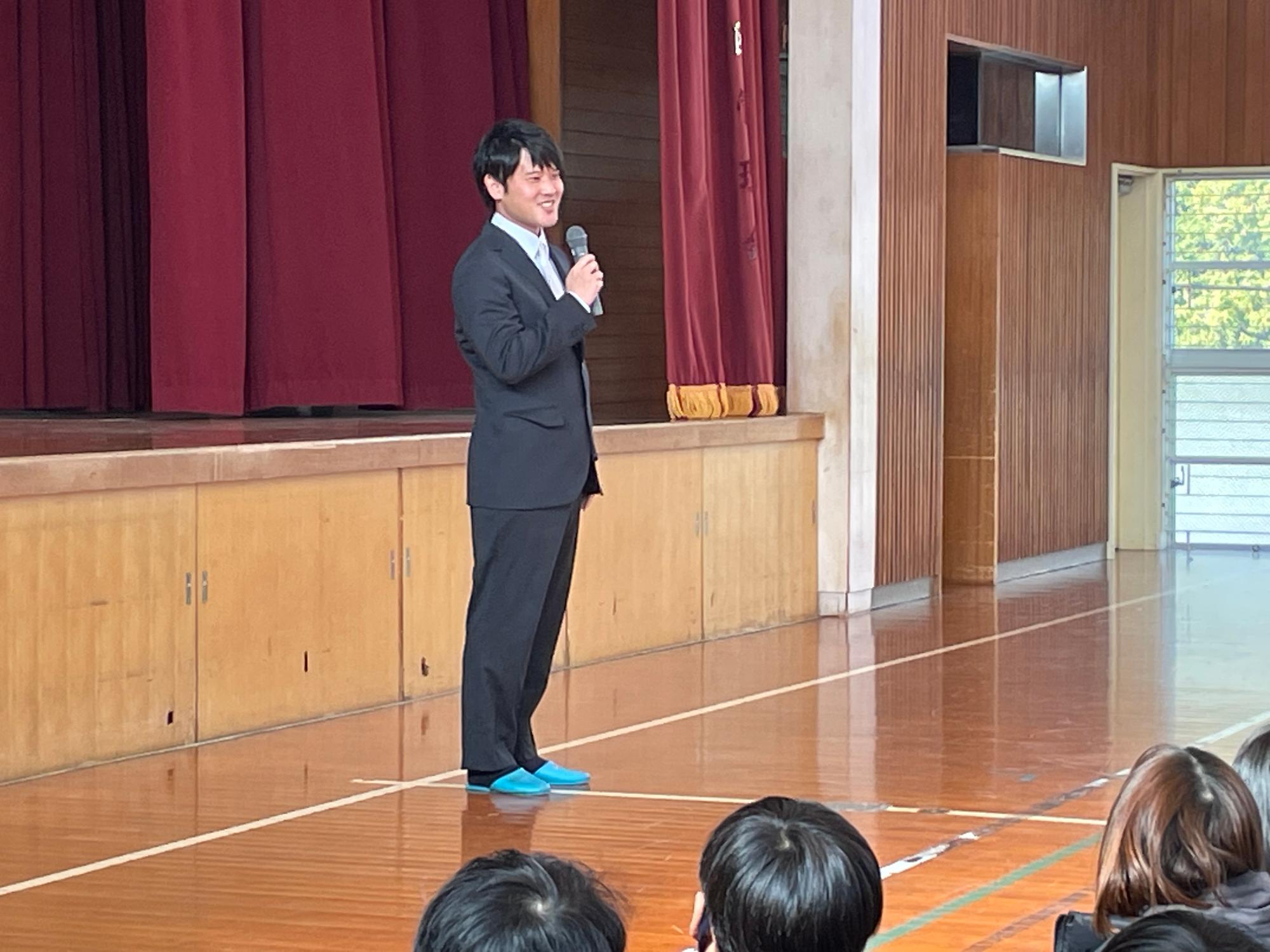 卒業生の橘さんが全校児童に向けてお話しをしている様子