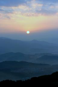 三日月山（みかづきやま）の山並みの奥から太陽の光が射している幻想的な写真