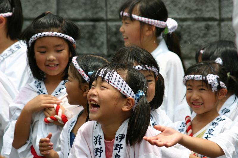 頭に鉢巻を巻き白色の法被を着た女の子たちが、水を浴びて満面の笑顔の写真