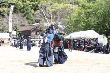 周りで観客が見守る中、屋外で剣道の試合を行っている写真