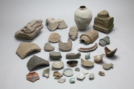 発掘された壺や数々の食器の欠片などの遺跡品が並んでいる写真