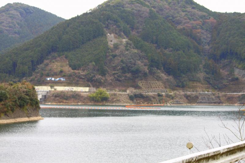 山の斜面に猪野ダムと大きく表示されている手前に広がるダムを道路から撮影した写真